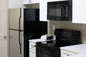 A kitchen with white cabinets and black appliances